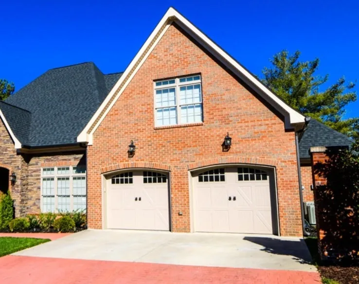 Two light carriage style garage doors on a brick home