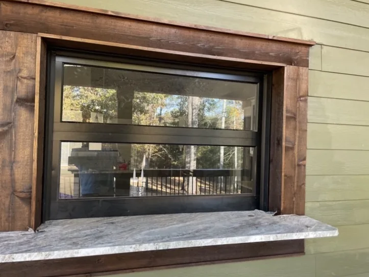 Glass residential pass-through garage door framed by stained wood trim
